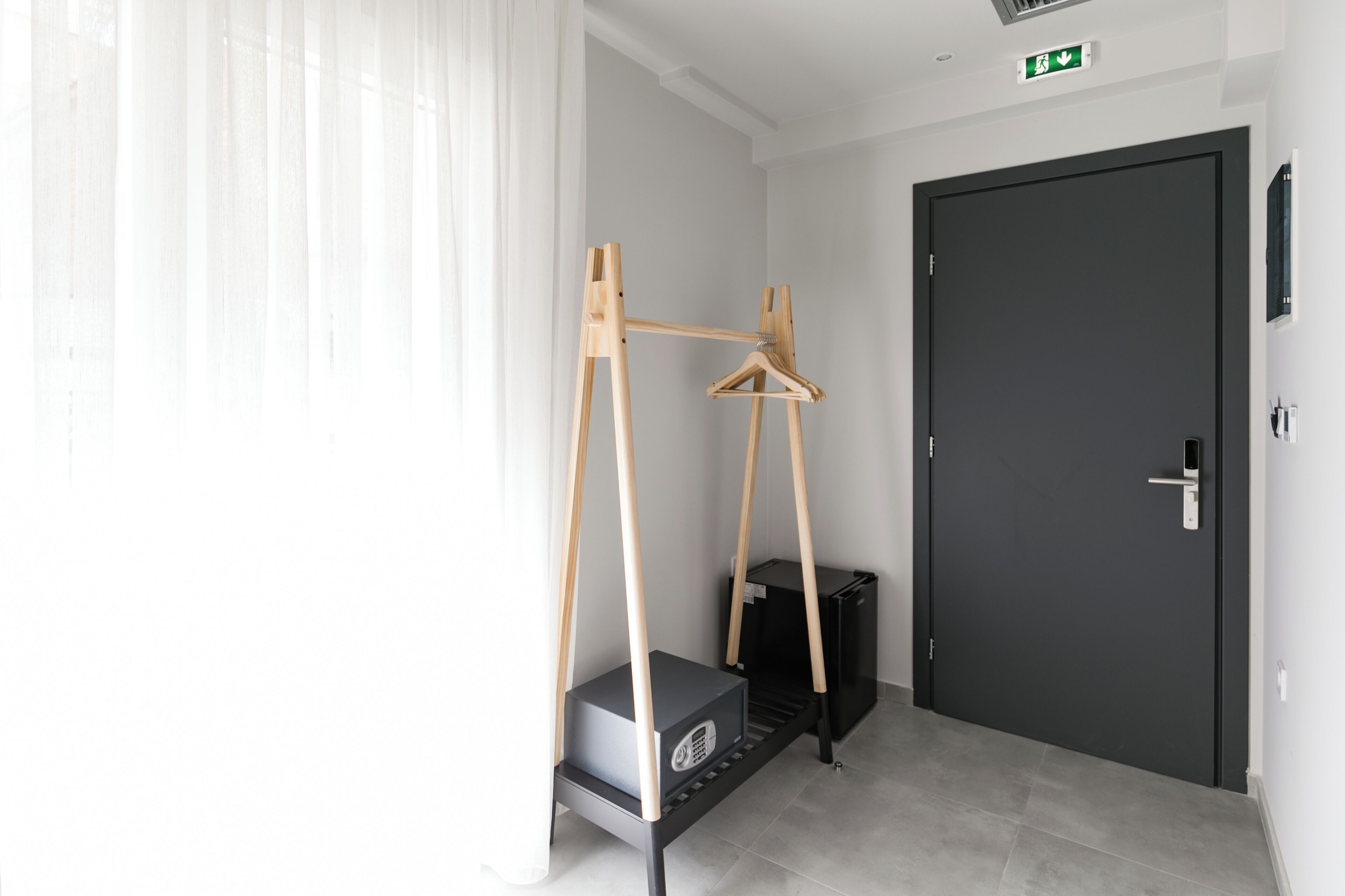 A room with a black door, a small black cabinet, and a wooden easel with a hanger.