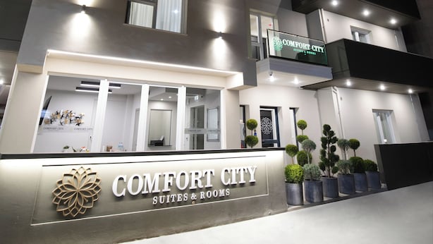 A multi-story hotel with a sign reading "COMFORT CITY SUITES & ROOMS" at the entrance.