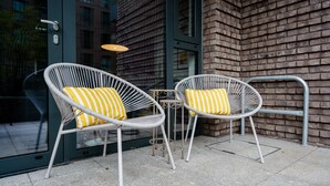 Two wicker chairs with yellow and white striped cushions, a small metal table, and a glass door with a metal handle.