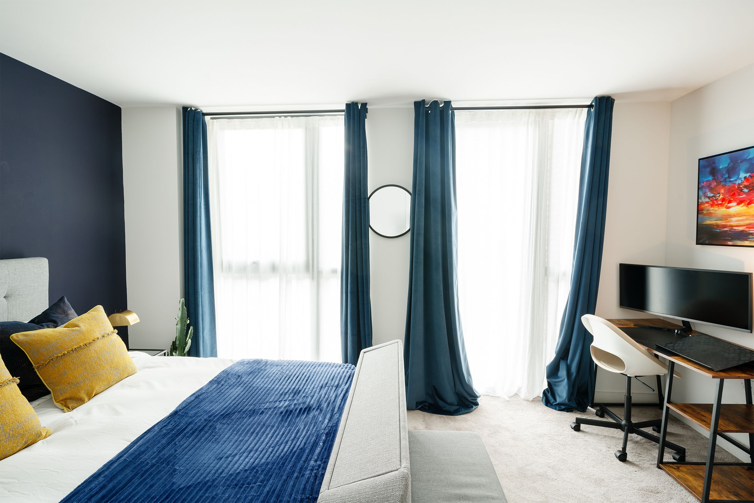 Quarto moderno com cama, escrivaninha e televisão.