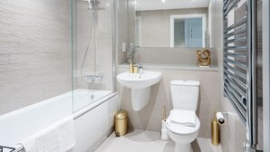 A modern bathroom with a glass-enclosed shower, a white bathtub, a sink, and a toilet.