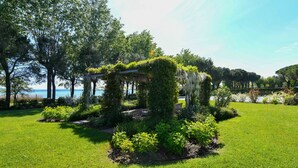 Un jardin agrémenté d’une pergola recouverte de verdure, entouré de pelouse et d’arbres bien entretenus.