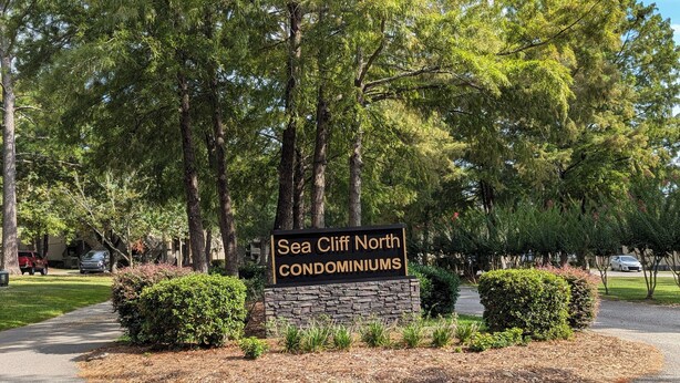 Un panneau indiquant le complexe résidentiel Sea Cliff North, entouré d’arbres et bordé par une allée.