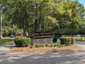 A sign for Sea Cliff North Condominiums surrounded by trees and a driveway. - Fun Little Studio in Daphne - Great location (Daphne)
