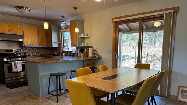 Una cocina moderna con una isla central, sillas amarillas y una mesa de comedor.