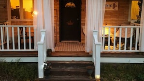 A house with a dark front door, white curtains, and a small porch with white railings. - Orchard Apartment @ The Copper Crown, Bayfield (Bayfield)