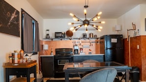 A modern kitchen with a central island, black appliances, and a unique light fixture. - Orchard Apartment @ The Copper Crown, Bayfield (Bayfield)