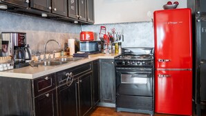A kitchen with a red refrigerator, a stove, a microwave, and dark wooden cabinets. - Outer Island Apartment @ The Copper Crown (Bayfield)