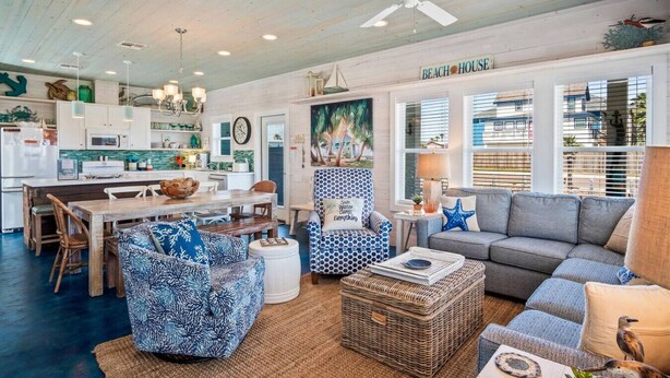A spacious living room with a dining area, a kitchen, and a large window with blinds. - `Escape to Endless Summer: Morning coffee, and BBQs, with access to two community pools for endless family fun!` (Port Aransas)