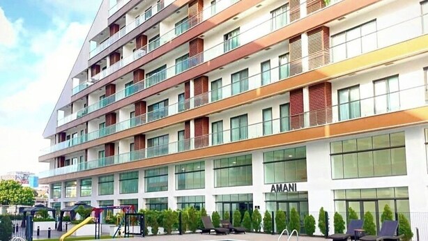 Un hôtel à plusieurs étages doté d’une piscine, d’un espace extérieur aménagé et d’une façade bien visible sur laquelle figure le nom de la marque, « AMANI ».