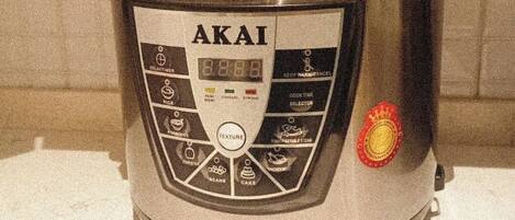 A compact, stainless steel, electric pressure cooker with a digital display and multiple cooking settings.