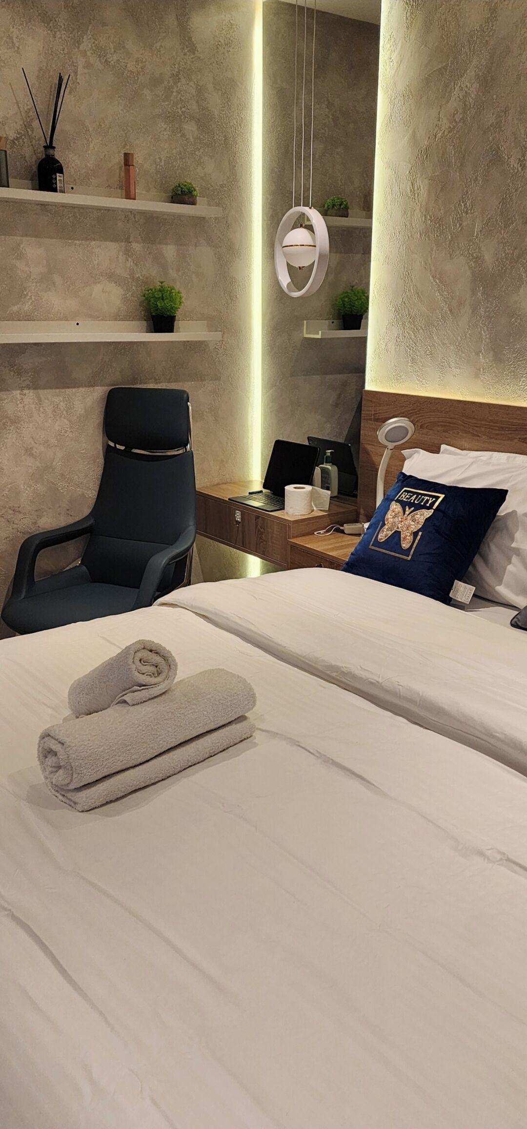 Una habitación de hotel moderna con una cama, un escritorio, una silla y una mesita de noche.