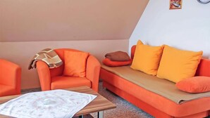 Ein Zimmer mit einem Holztisch, einem orangefarbenen Sofa und einem passenden Sessel.