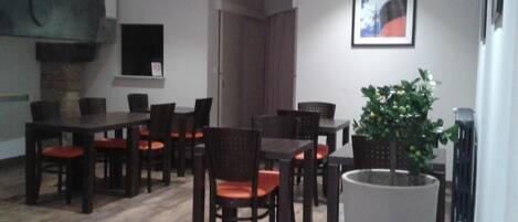 Un comedor con mesas y sillas de madera, una planta en maceta y una chimenea.