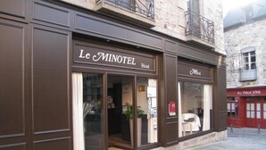 Un hotel anomenat "Le Minotel" amb una façana clàssica, grans finestres i un entrada ben visible.