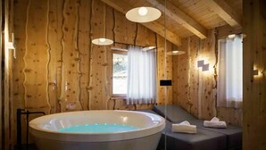 A wooden cabin interior with a large bathtub, a sofa, and a window with curtains. - Impeccable 4-bed Villa in Cadin di Sotto (Cortina d'Ampezzo)