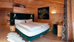A wooden cabin bedroom with a bed, a headboard, a wall painting, a wooden cabinet, and a fur rug. - Impeccable 4-bed Villa in Cadin di Sotto (Cortina d'Ampezzo)