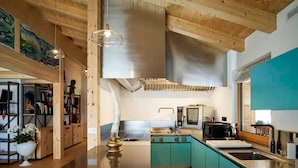 A modern kitchen with teal cabinets, stainless steel appliances, and a central island. - Impeccable 4-bed Villa in Cadin di Sotto (Cortina d'Ampezzo)