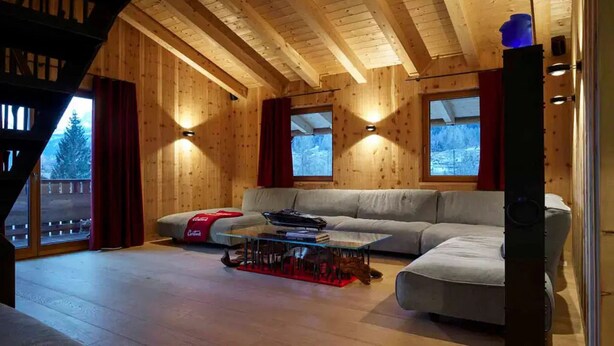 A cozy log cabin interior with a sofa, a coffee table, and a window with a view of a snowy landscape. - Impeccable 4-bed Villa in Cadin di Sotto (Cortina d'Ampezzo)