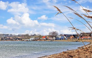 A lakeside view with houses and a clear sky. - Ferienwohnung Mönchgut (Mönchgut OT Alt Reddev)