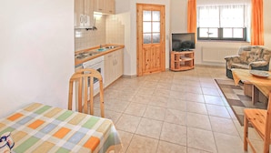 A compact living space with a kitchen, dining area, and a TV. - Ferienwohnung Mönchgut (Mönchgut OT Alt Reddev)