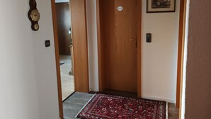 Un couloir avec une porte en bois portant l’inscription «PRIVÉ», une horloge fixée au mur, un petit tableau encadré et un tapis rouge à motifs sur le sol.