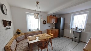 Une cuisine compacte avec un coin repas, comprenant un banc intégré, une table avec des sets de table, un réfrigérateur et une fenêtre donnant sur un paysage agréable.