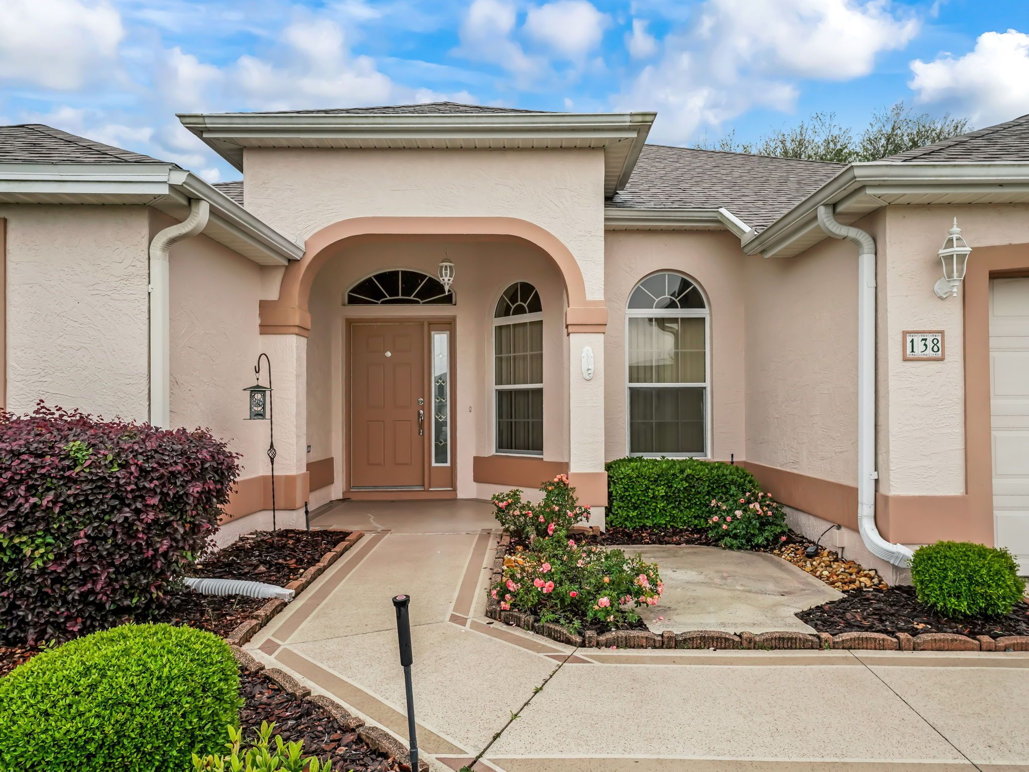 A two-story house with a beige facade, a brown front door, and a mailbox.