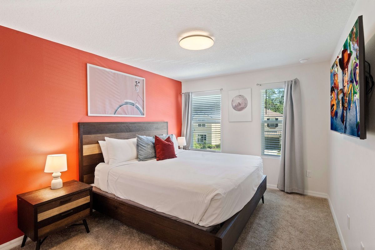 A bedroom with a bed, nightstand, and a painting on the wall.