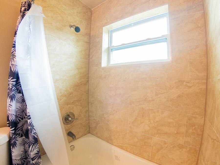 Un baño con ducha, ventana y bañera.