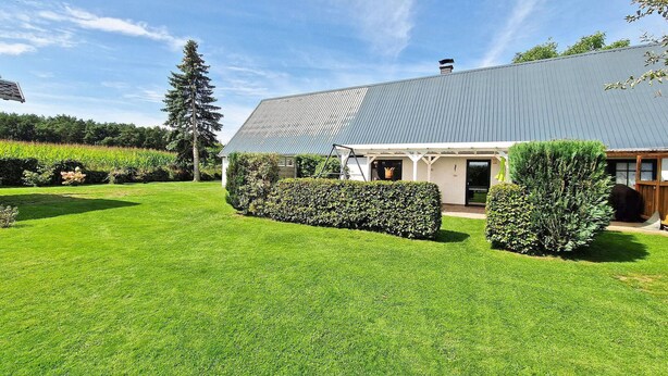 A modern house with a large lawn, a covered porch, and a metal roof.