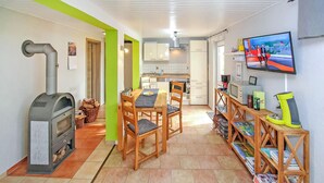 A modern kitchen with a dining area, a TV mounted on the wall, and a fireplace.
