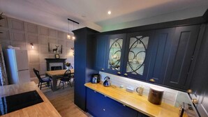 Una cocina moderna con armarios azul oscuro, encimera de madera y un comedor con mesa y sillas.