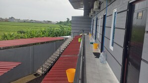 A covered outdoor area with a red carpet, a metal staircase, and a water dispenser. - Capital O 93816 Cerry Village (Tegal)