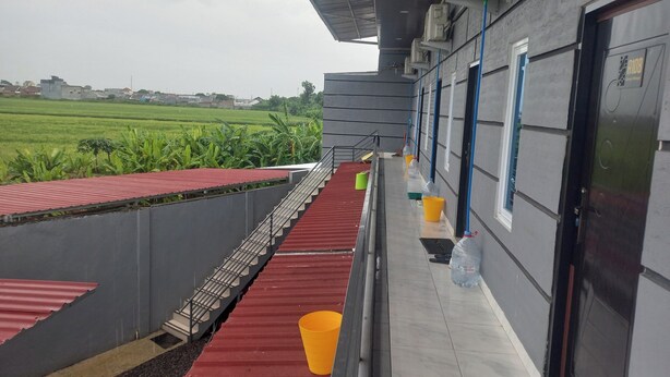 A covered outdoor area with a red carpet, a metal staircase, and a water dispenser. - Capital O 93816 Cerry Village (Tegal)