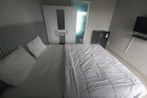 A hotel room with a bed, a wardrobe, a television, and a small cabinet.