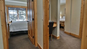 Een slaapkamer met een bed, een bureau en een raam met uitzicht op bomen.