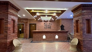 A hotel reception area with a brick wall, a reception desk, and two wicker chairs. - Hotel Kesu Home (Kathmandu)