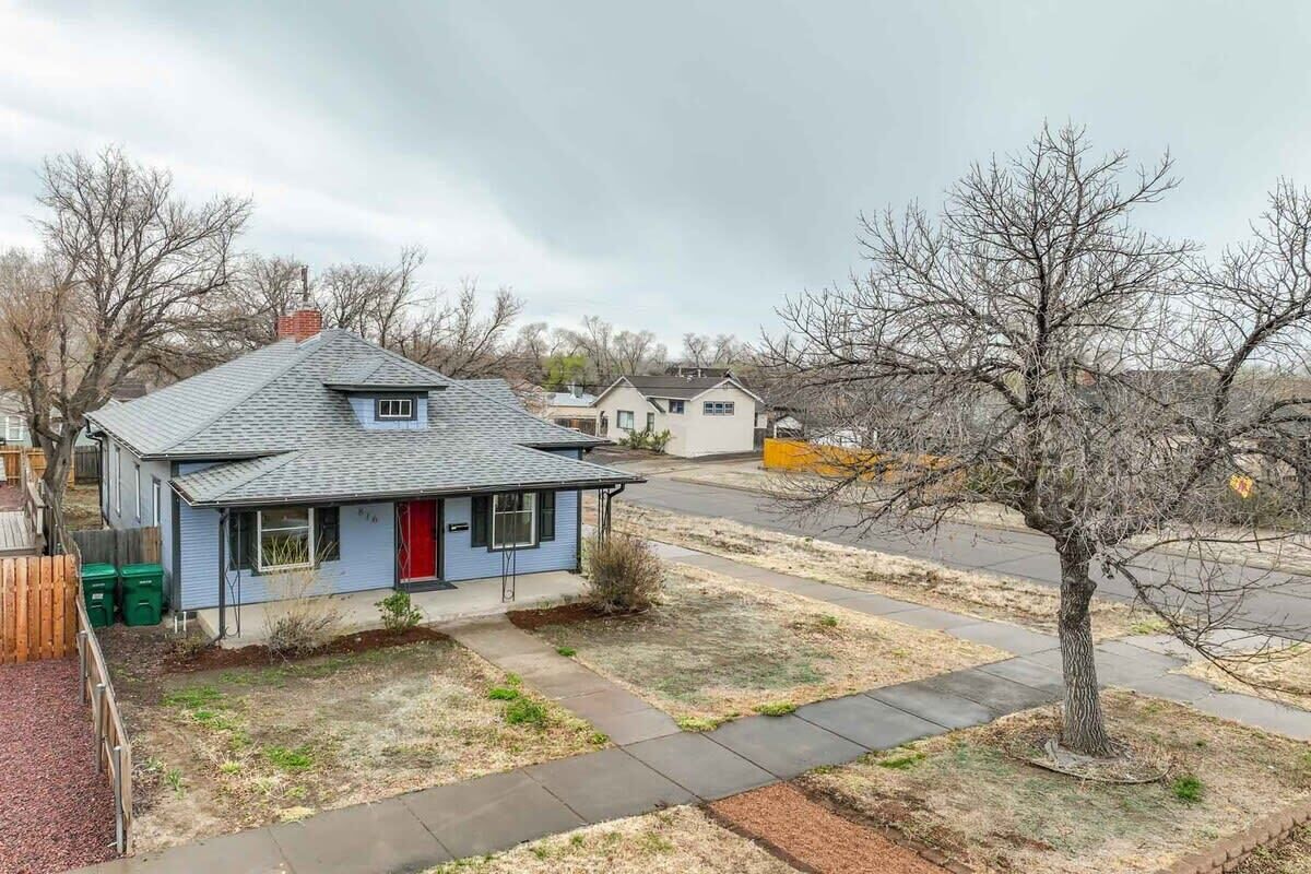 A residential area with houses, a sidewalk, and a tree.