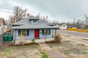 A single-story house with a red door, a small front yard, and a sidewalk leading to the street.