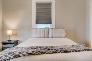 Une chambre à coucher avec un lit, une table de chevet avec une lampe et une fenêtre avec des stores.