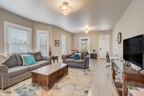 Un salon spacieux avec un canapé gris, une table basse et un téléviseur posé sur un meuble en bois.