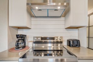 A modern kitchen with stainless steel appliances, including a coffee maker, a stove, and a toaster.