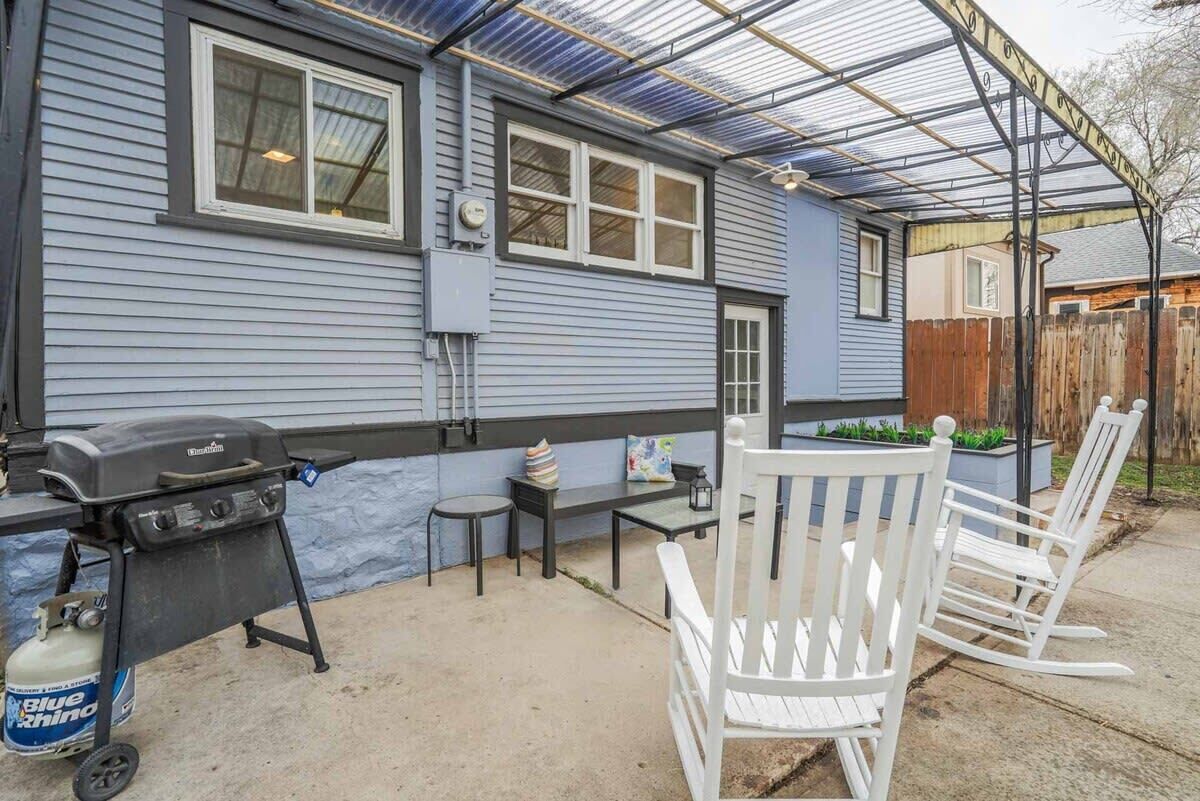 A covered patio area with a grill, seating, and a gas canister.