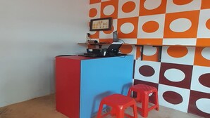 A room with a desk, two red stools, and a patterned wall. - Hotel O Fermansio Homestay 2 (Medan)