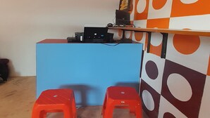 A room with a blue desk, two red stools, and a wall with a geometric pattern. - Hotel O Fermansio Homestay 2 (Medan)