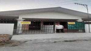 A building with a gated entrance, a signboard, and a person standing near the gate. - Hotel O Fermansio Homestay 2 (Medan)