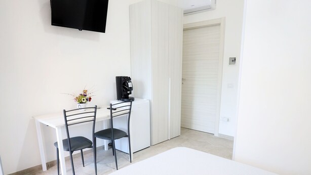 A bedroom with a bed, a desk with a chair, a television on the wall, and a wardrobe. - B&B REVOLUTION BED & BREAKFAST (Caserta)