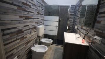 Un baño moderno con ducha, dos bidés, inodoro y lavamanos.