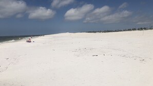 A beach with white sand and a clear blue sky.